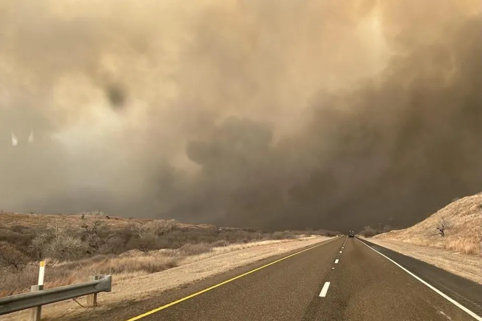 Two-lane asphalt road with smoke filling the sky in Texas Panhandle.